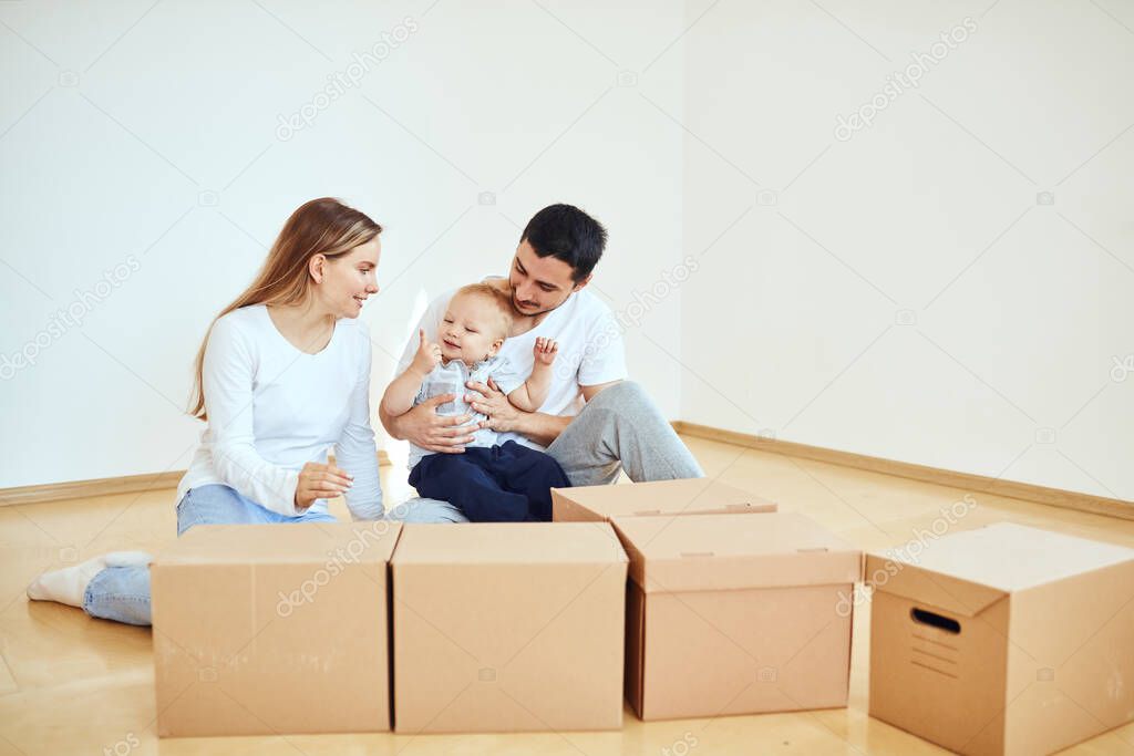 Family with boy unpacking moving cardboard boxes at new home