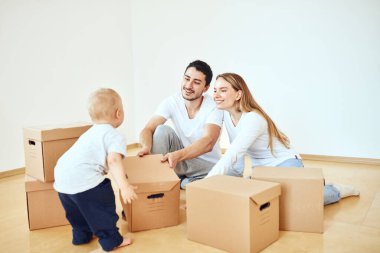 Yeni evimizde karton kutuları açan çocukla aile.