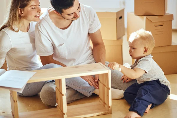 Familj tillsammans i vardagsrummet i ny lägenhet montera möbler, hög med rörliga lådor på bakgrunden — Stockfoto