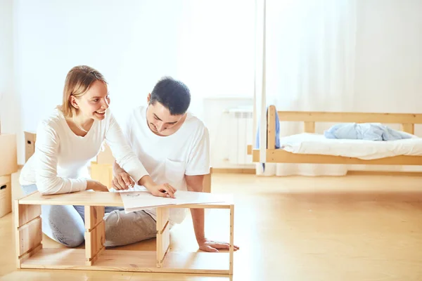 Casal instalar móveis em casa nova com instrução — Fotografia de Stock