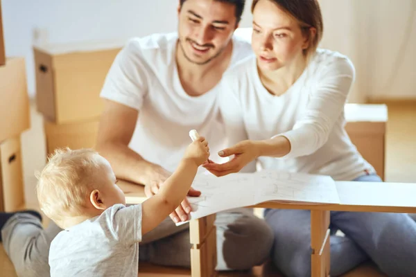 Family reading instruction and assemble furniture together at living room of new apartment pile of moving boxes on background — Stock Photo, Image