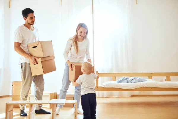 Niño pequeño que lleva la caja en movimiento, los padres en un fondo borroso. Concepto móvil — Foto de Stock