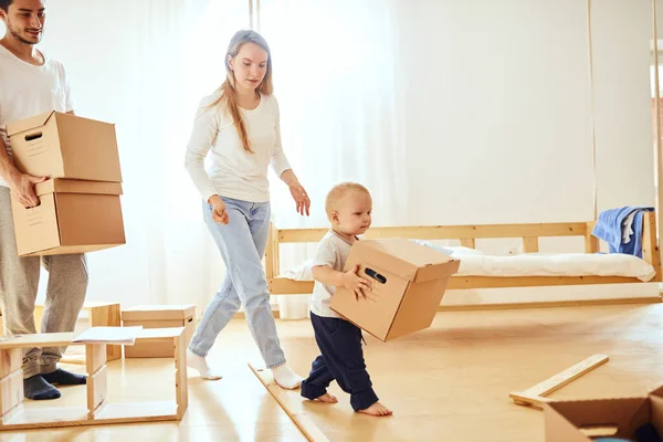 Niño pequeño que lleva la caja en movimiento, los padres en un fondo borroso. Concepto móvil —  Fotos de Stock