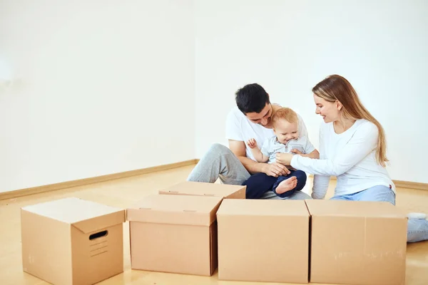 Familia con niño desempacando cajas de cartón móviles en un nuevo hogar —  Fotos de Stock