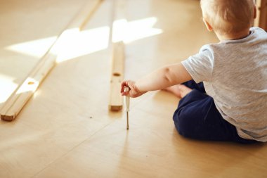 Aile, yeni apartmanın oturma odasında mobilya montajı, arka planda taşınan kutular.