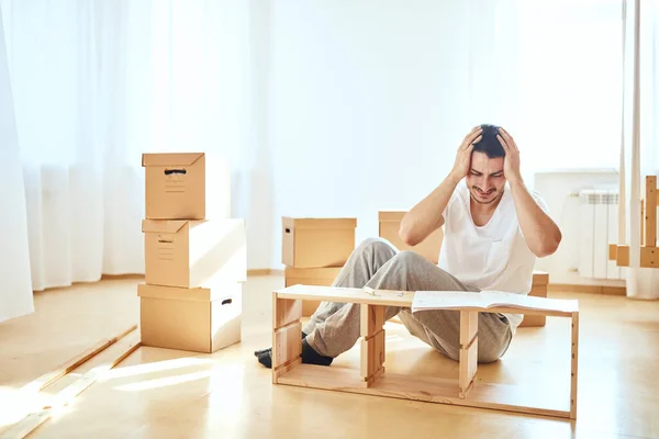 Concentrated man reading instructions to assemble furniture at home — Stock Photo, Image