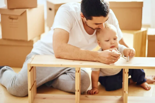 Far och son monterar möbler hemma — Stockfoto