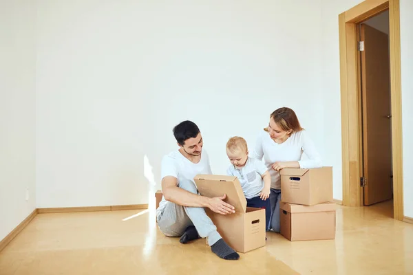 Familia con niño desempacando cajas de cartón móviles en un nuevo hogar — Foto de Stock