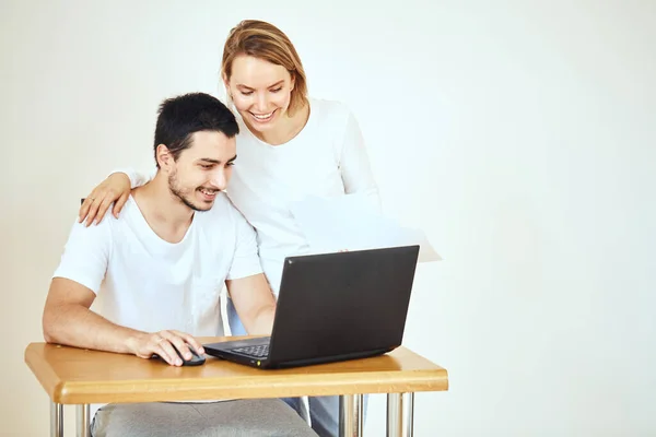 Счастливая пара дома оплачивает счета с ноутбука — стоковое фото