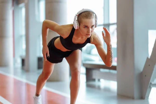 Joven rubia corriendo mujer con auriculares en la pista — Foto de Stock