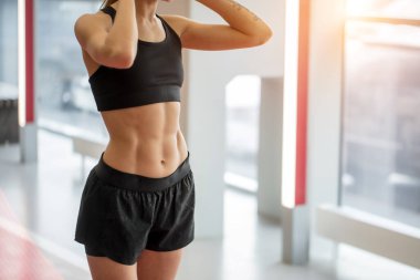 Kapat. Spor salonunda kırmızı yolda duran genç bir kadın.