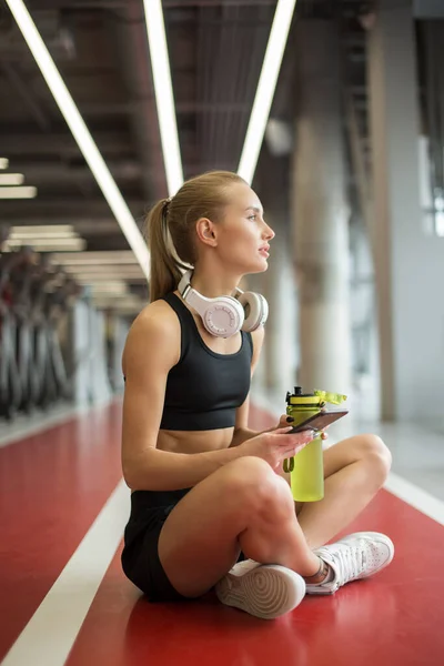 Frau mit Handy auf dem Boden sitzend, Wasserflasche in der Hand, plauderndes Smartphone — Stockfoto