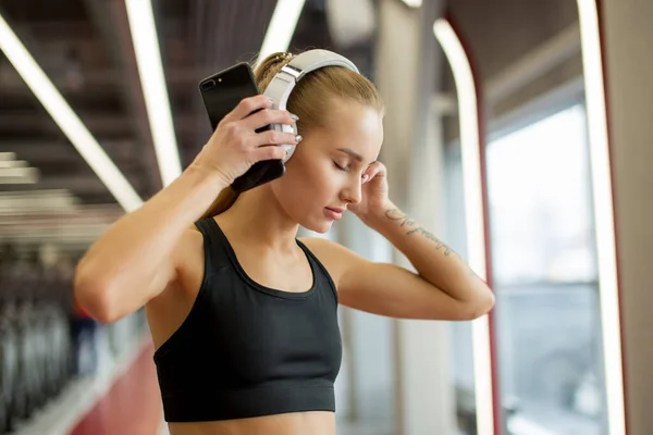Спорт і музика. жінка тримає навушники під час роботи в спортзалі — стокове фото