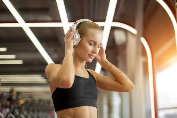 Спорт і музика. жінка тримає навушники під час роботи в спортзалі — стокове фото