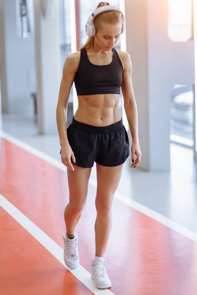 Mujer con el pelo rubio de pie en el club de salud. hermosa mujer fitness en el gimnasio. — Foto de Stock