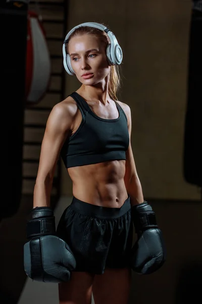 Дівчина в чорних боксерських рукавичках позує в спортзалі — стокове фото