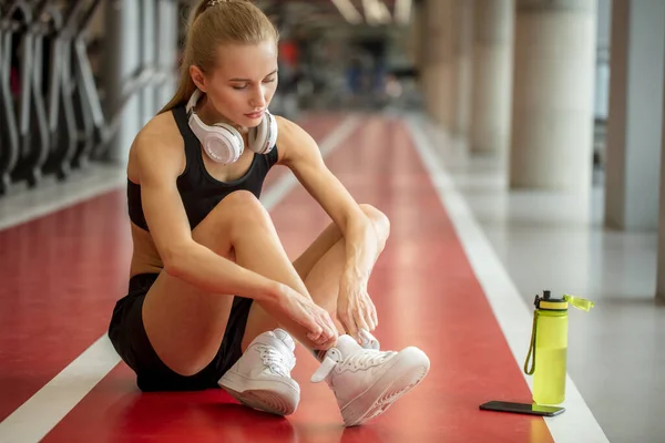 Дівчина зав'язує шнурки у фітнес-тренажерному залі перед тренуванням вправ для кардіо — стокове фото