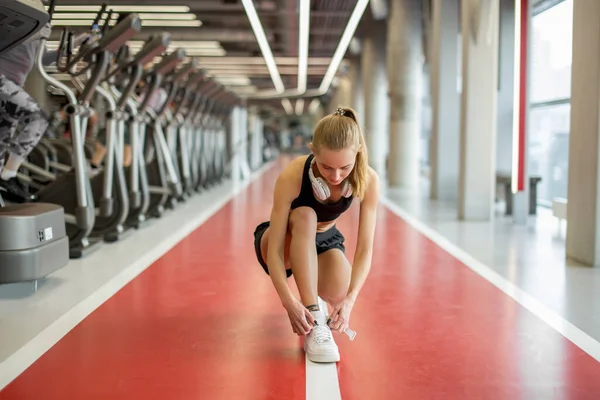 Kardiyo antrenmanından önce spor salonunda ayakkabı bağı bağlayan bir kız. — Stok fotoğraf