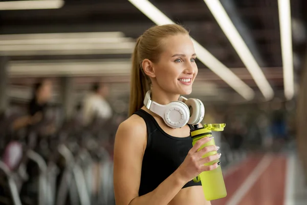 Blonde athletische Frau in Schwarz schließt Trinkwasser in Turnhalle — Stockfoto