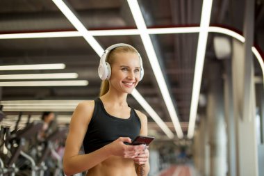 Spor salonunda akıllı telefon kullanan aktif sarışın kadın spor giyim..