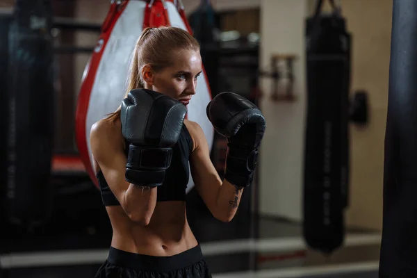 Eldivenli kadın boksör savunma pozisyonunda duruyor ve bir tarafa odaklanmış görünüyor. — Stok fotoğraf