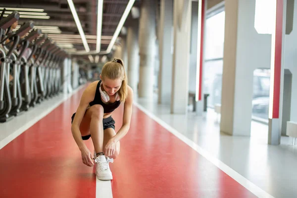 Mädchen bindet Schnürsenkel in Fitnessstudio, bevor sie Ausdauertraining macht — Stockfoto