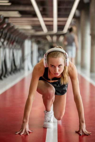 Mujer rubia con ropa deportiva preparada para correr. pose de inicio bajo — Foto de Stock