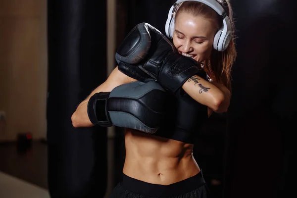 Combatiente femenina con guantes de mano se prepara para el ejercicio en el saco de boxeo —  Fotos de Stock