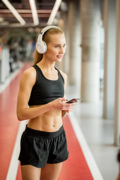 Ropa deportiva de mujer rubia activa con teléfono inteligente en el gimnasio. — Foto de Stock