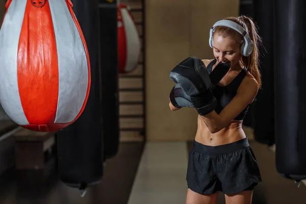 Combatiente femenina con guantes de mano se prepara para el ejercicio en el saco de boxeo —  Fotos de Stock