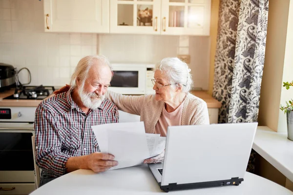 Sorridente coppia matura con documenti e laptop in casa interna — Foto Stock