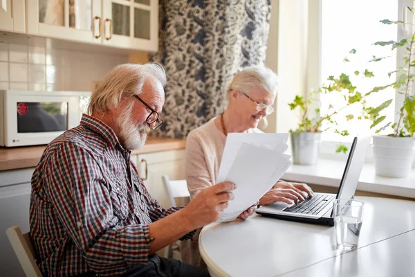 Sorridente coppia matura con documenti e laptop in casa interna — Foto Stock