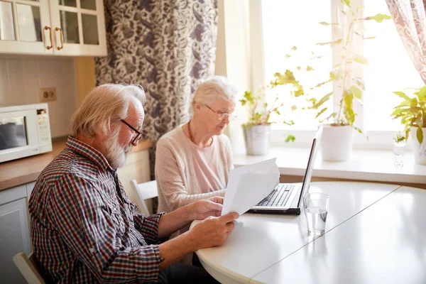 Sorridente coppia matura con documenti e laptop in casa interna — Foto Stock