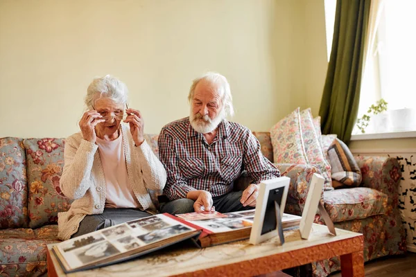 Старі люди дивляться на свій фотоальбом вдома — стокове фото