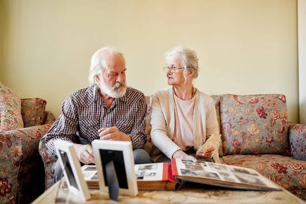 Senioren betrachten ihr Fotoalbum zu Hause — Stockfoto
