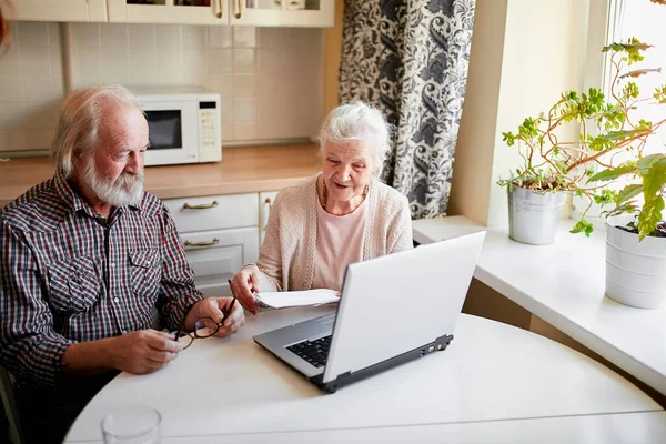 Sorridente coppia matura con documenti e laptop in casa interna — Foto Stock