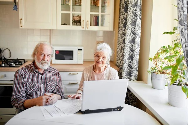 Sorridente coppia matura con documenti e laptop in casa interna — Foto Stock