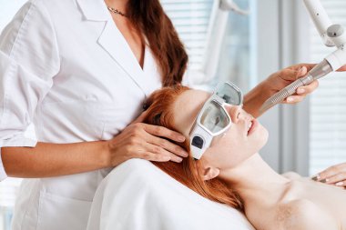 Woman getting laser face treatment in medical center, skin rejuvenation concept clipart