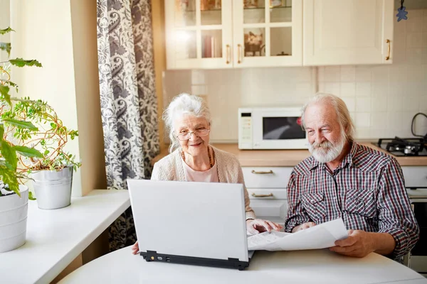 Sorridente coppia matura con documenti e laptop in casa interna — Foto Stock