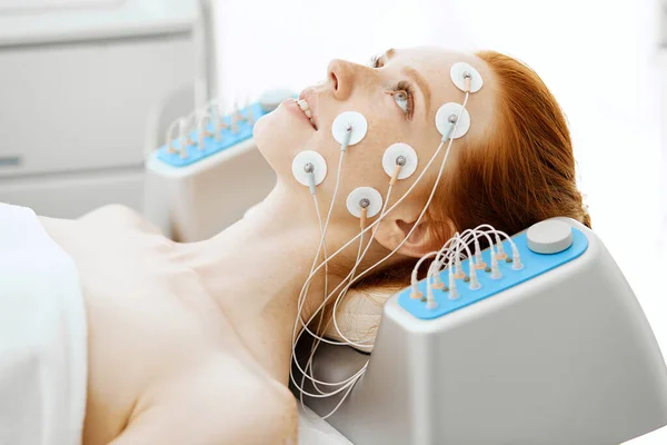 Mujer joven con electrodos en la cara, recibiendo estimulación eléctrica. — Foto de Stock