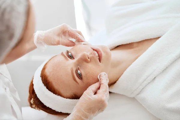 Cosmetologist clinsing with cotton pad female face preparing for procedure. — Stock Photo, Image