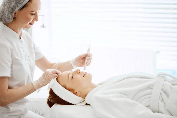Een vrouw die gezichtsbehandeling krijgt in een schoonheidscentrum. Vloeibare peeling van het gelaat — Stockfoto