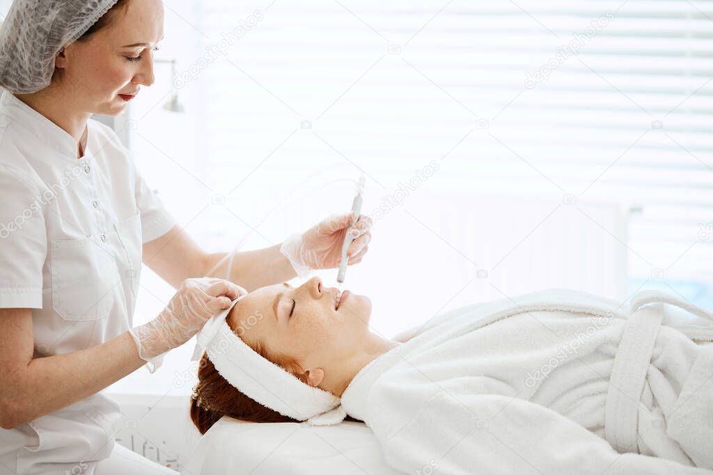 Woman getting face peeling procedure in beauty centre. Facial gas liquid peeling
