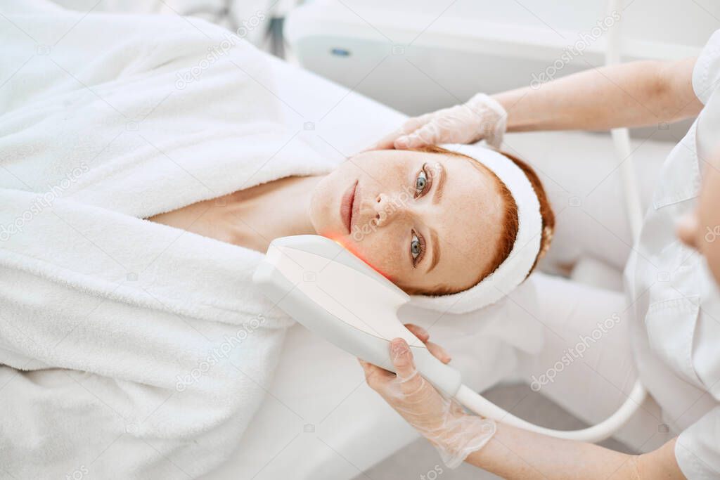 Ultrasound infrared cosmetology procedure for face, top view, beauty treatment.