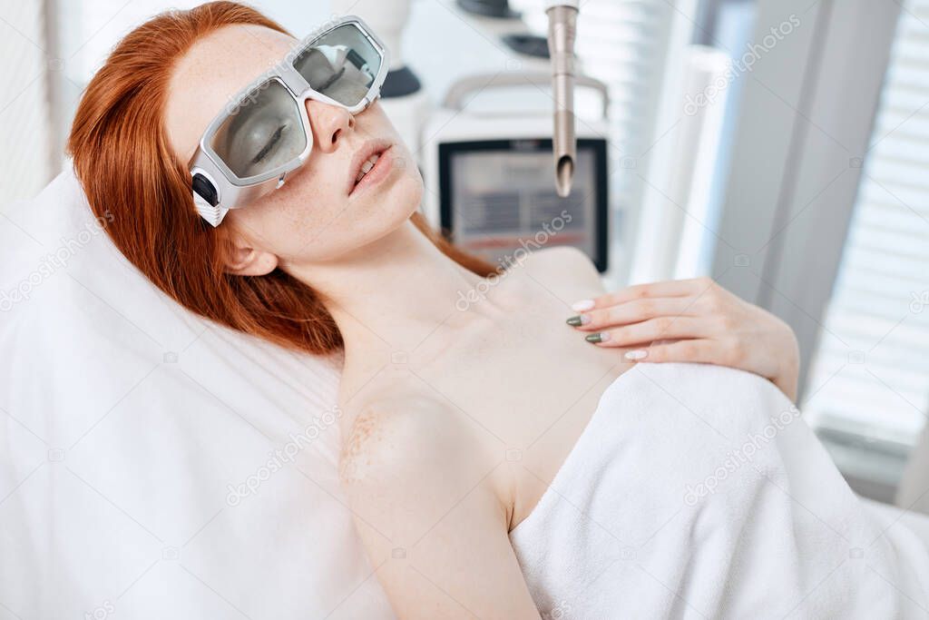 Woman getting laser face treatment in medical center, skin rejuvenation concept