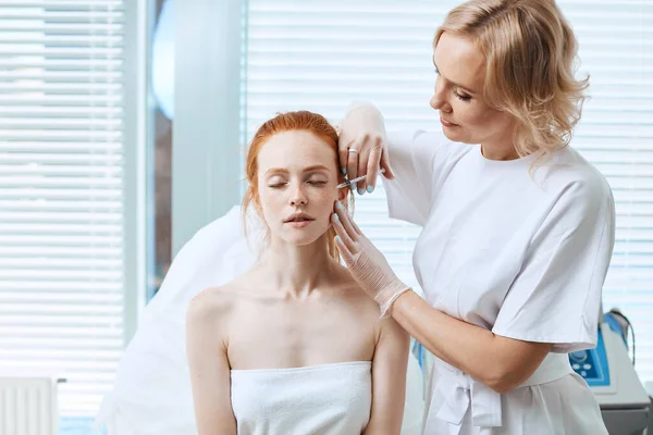 Kaukázusi vörös hajú nő kap kozmetikai arcinjekciót. Arcöregítő injekció. — Stock Fotó