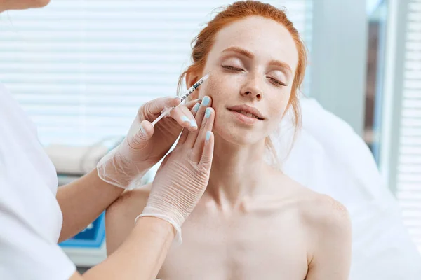 Caucasian red-haired woman gets beauty facial injections. Face aging injection. — Stock Photo, Image