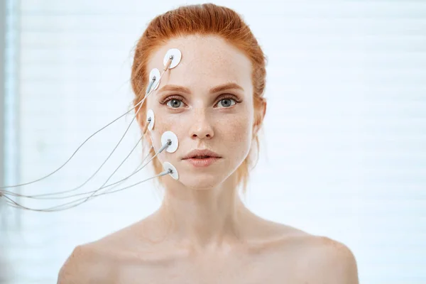Femme avec des électrodes sur son visage, recevant une stimulation électrique sur sa peau. — Photo