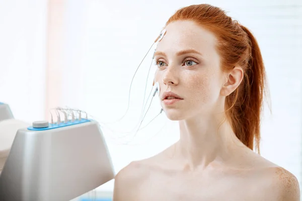 Mujer con electrodos en la cara, recibiendo estimulación eléctrica en la piel. — Foto de Stock