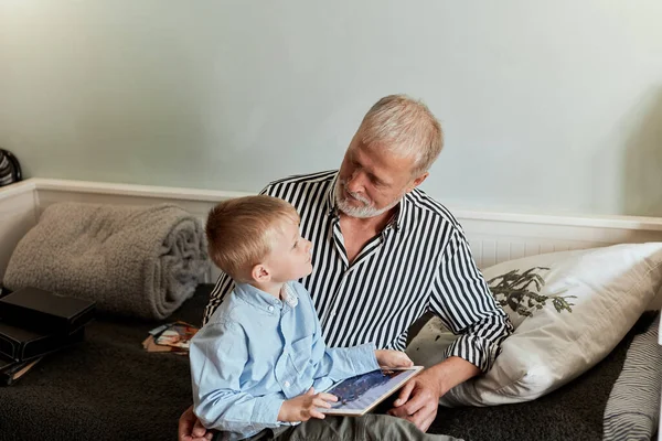 Abuelo y nieto usando tableta digital mientras están sentados en el sofá — Foto de Stock